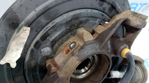 Общий вид задней правой цапфы Jeep Grand Cherokee с тросом ручника на фоне маркировки.