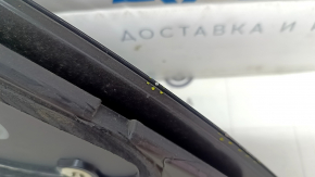Подробное изображение края комплекса задней левой форточки Tesla Model Y, видны мелкие следы использования.