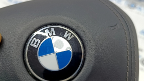 Детальный вид логотипа BMW на подушке безопасности руля, заметен небольшой дефект.