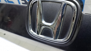 Крупный план эмблемы Honda на молдинге, видимые повреждения