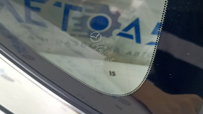 Крупный план маркировки стекла форточки Mazda, подтверждающей оригинальность детали.