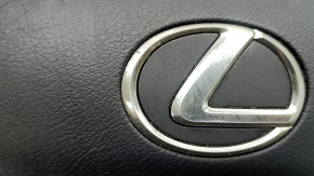 Крупный план слегка поврежденного логотипа Lexus на подушке безопасности.