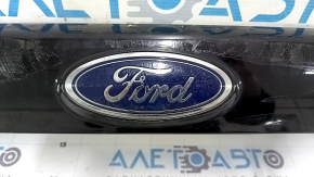 Эмблема Ford на молдинге, без значительных повреждений, видно состояние детали вблизи.