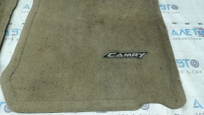 Крупный план коврика с логотипом Camry, видимые потёртости на поверхности.