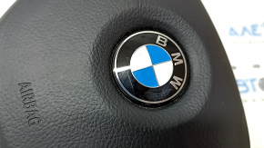 Крупный план на значок BMW на подушке безопасности, видно естественные следы износа.