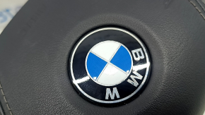 Крупный план эмблемы на подушке безопасности руля BMW 5 G30, видно легкую коррозию.
