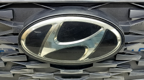 Близкий план эмблемы Hyundai на решетке, демонстрирующий состояние и легкие потертости.