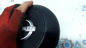 Крупный план подушки безопасности Nissan с царапинами, цвет черный.