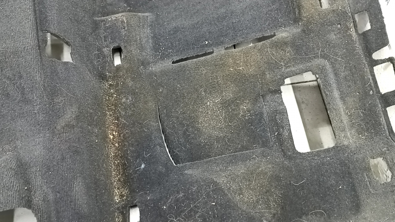 Деталь покрытия пола Audi Q5 с примесью грязи и повреждением.