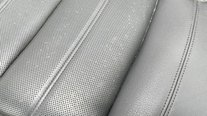 Крупный план перфорированной кожи заднего ряда сидений Audi A6, с заметным износом.