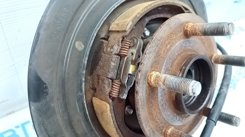 Детальный ракурс механизма стояночного тормоза задней правой цапфы Jeep Grand Cherokee, mostrando следы использования.