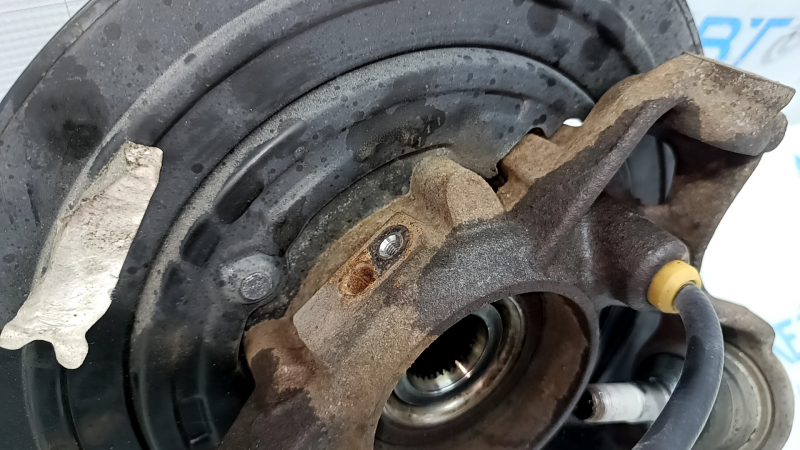 Общий вид задней правой цапфы Jeep Grand Cherokee с тросом ручника на фоне маркировки.