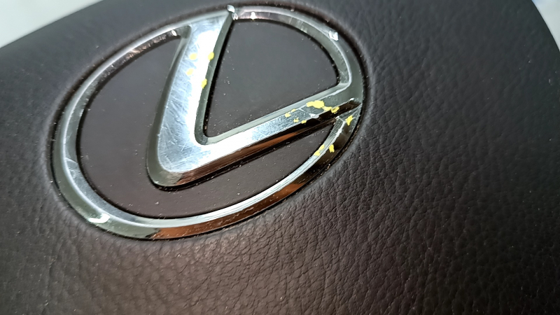 Детальный обзор логотипа Lexus с показом следов использования.