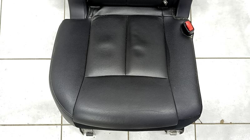 Крупный план сиденья Nissan Rogue, видно повреждения и потёртости на кожаной обшивке.