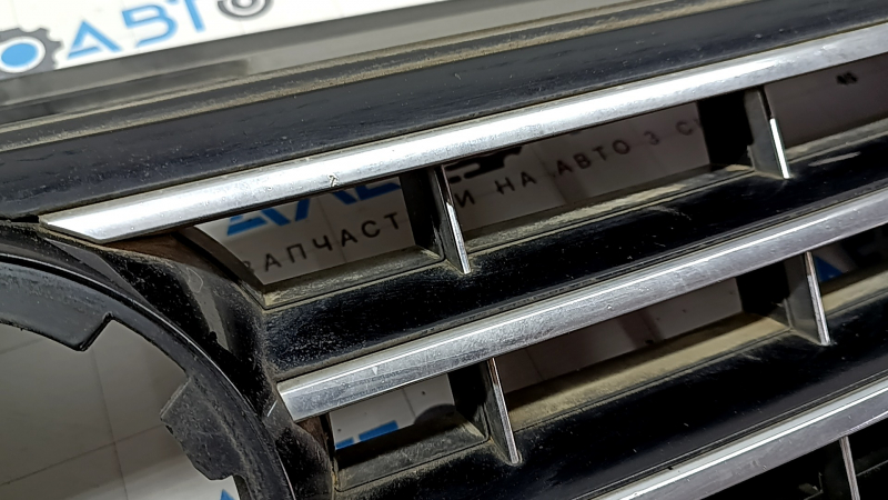 Крупный план решетки радиатора VW Passat 2016-2019 годов с потертостями и царапинами на поверхности