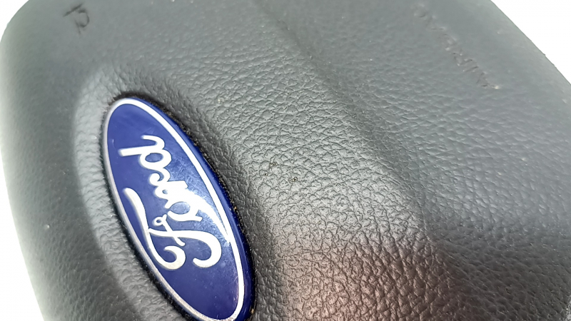 Боковой ракурс подушки безопасности с логотипом Ford, показывающий состояние поверхности.