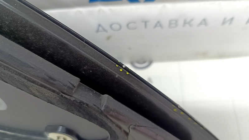 Подробное изображение края комплекса задней левой форточки Tesla Model Y, видны мелкие следы использования.