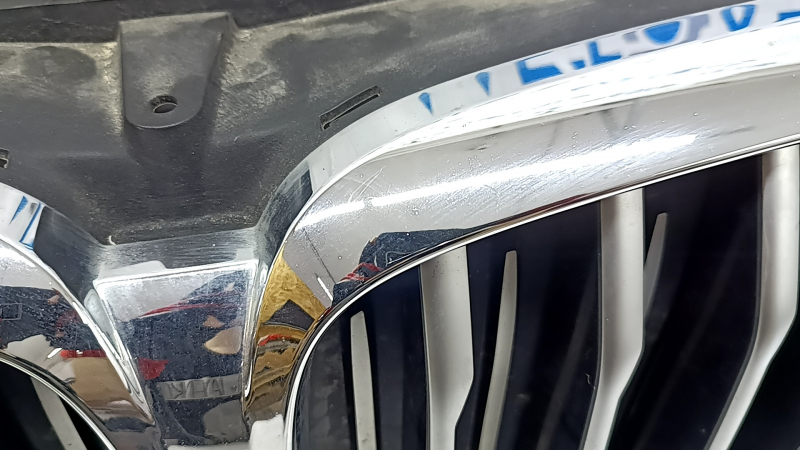 Крупный план хромированной части решетки радиатора BMW, заметны следы использования