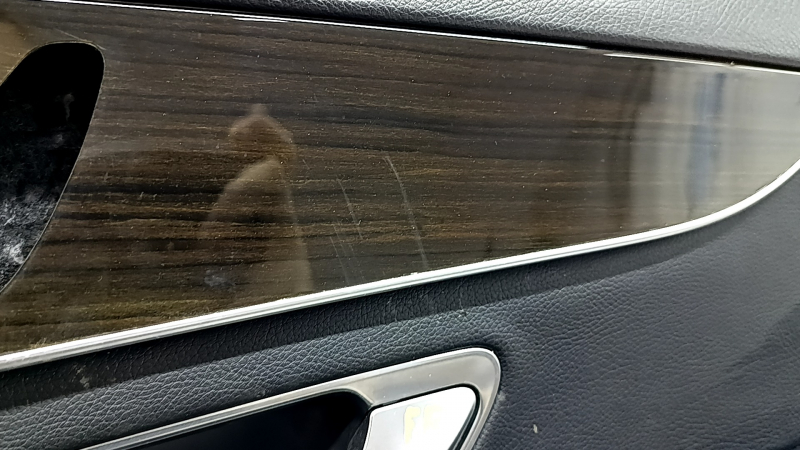 Крупный план вставки под дерево на обшивке Mercedes C-class W205, видимые следы царапин.