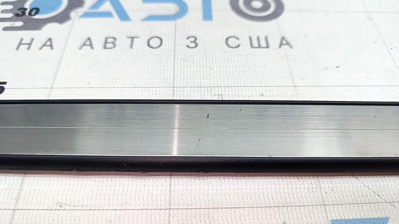 Крупный план хромированной накладки порога, царапины на отделке.