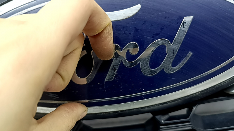 Трещина на эмблеме Ford, рассматриваемая на большом плане.