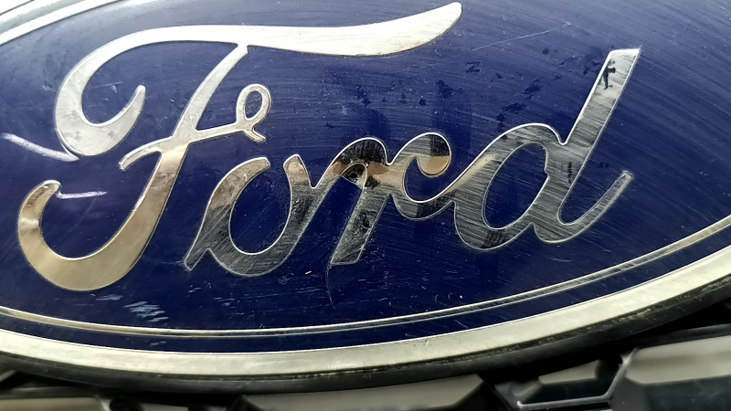 Крупным планом эмблема Ford с видимыми повреждениями.