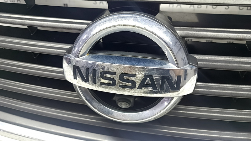 Логотип Nissan на решетке радиатора, с потертостями хрома, общий вид.