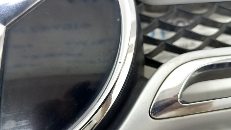 Крупный план эмблемы на решетке радиатора Mercedes, с мелкими царапинами