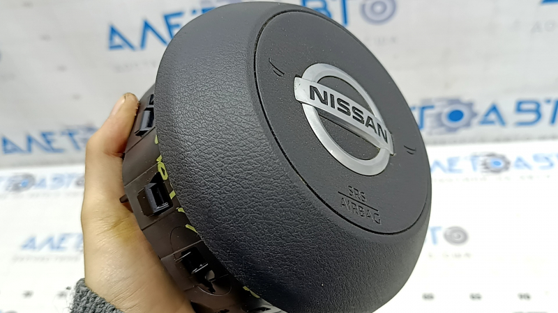 Деталь в руках с боку, подушка безопасности для Nissan Rogue, видна маркировка