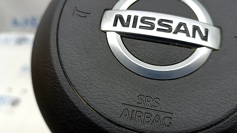 Фокус на логотипе Nissan и указание SRS AIRBAG на корпусе подушки