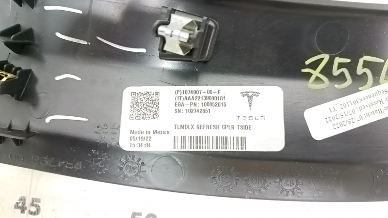 Крупный план с оригинальным номером накладки проема для Tesla Model X, указывающий на детали производства.