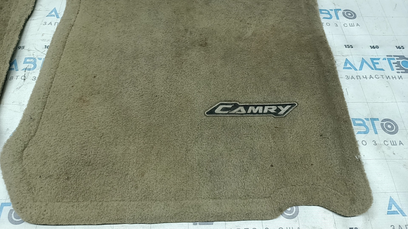 Крупный план коврика с логотипом Camry, видимые потёртости на поверхности.