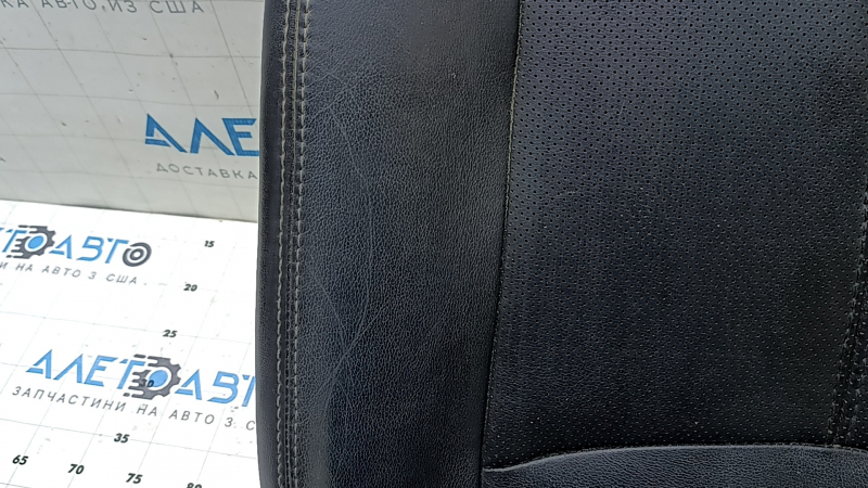 Крупный план черной перфорированной кожи на подушке пассажирского сиденья Mazda Pathfinder, есть незначительные дефекты.