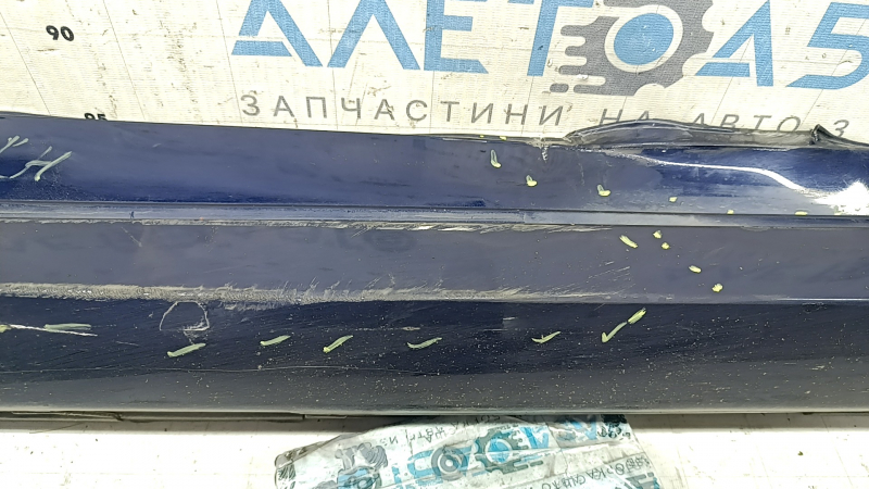 Крупный план повреждений на накладке порога, включая царапины и надлом крепления.