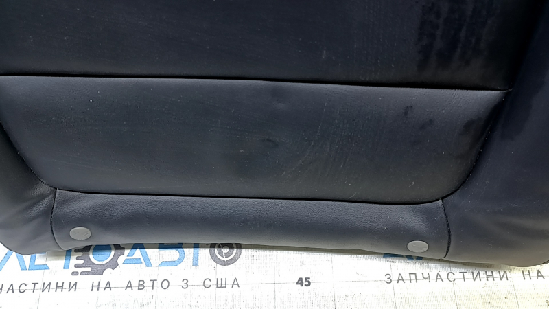 Крупный план поврежденной кожи спинки сидения Mazda 6, заметны следы использования.