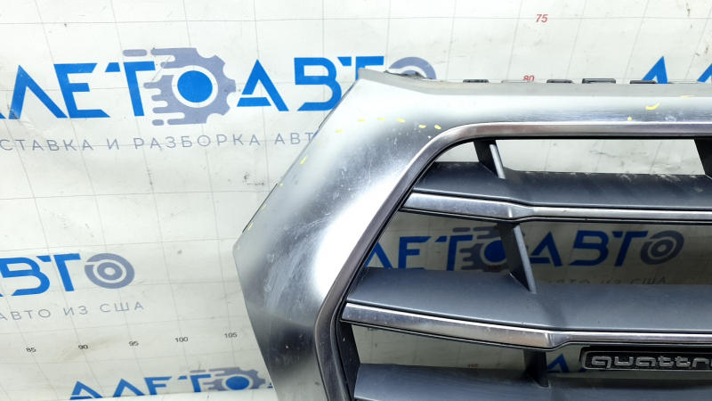 Крупный план поврежденной области хрома решетки радиатора Audi Q5, видны тычки.