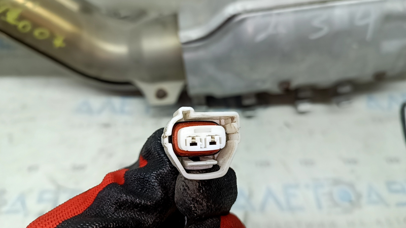 Крупный план разъёма на приемной трубе, который соответствует модели Nissan Rogue 2021-2026, состояние требует проверки.