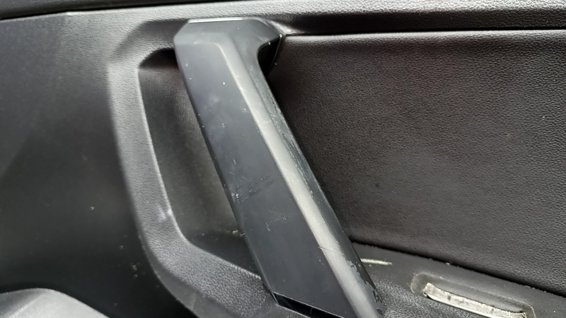 Ручка на обшивке двери Volkswagen Tiguan, здесь видно состояние пластика и признаки износа.