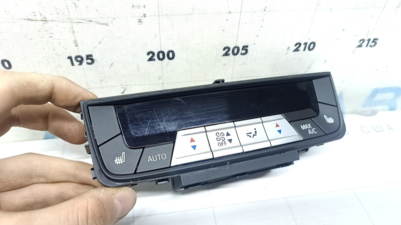 Рука держит панель климат-контроля для BMW X5 G05, на экране заметны следы использования