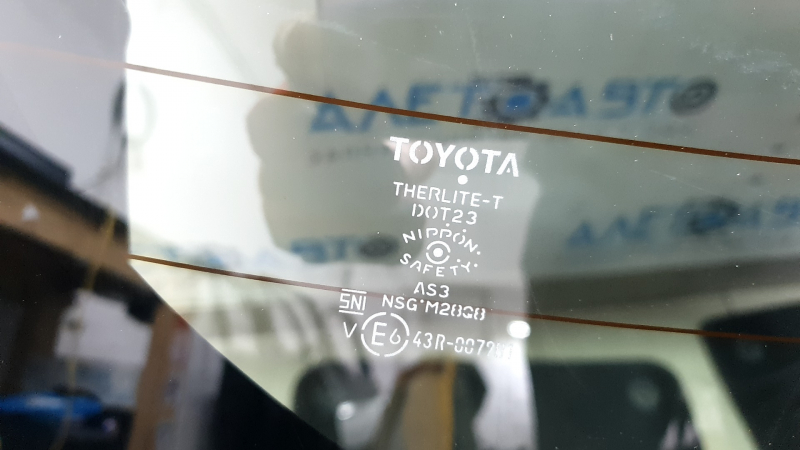 Близкий план маркировки на стекле двери багажника Toyota, подтверждающий оригинальность.