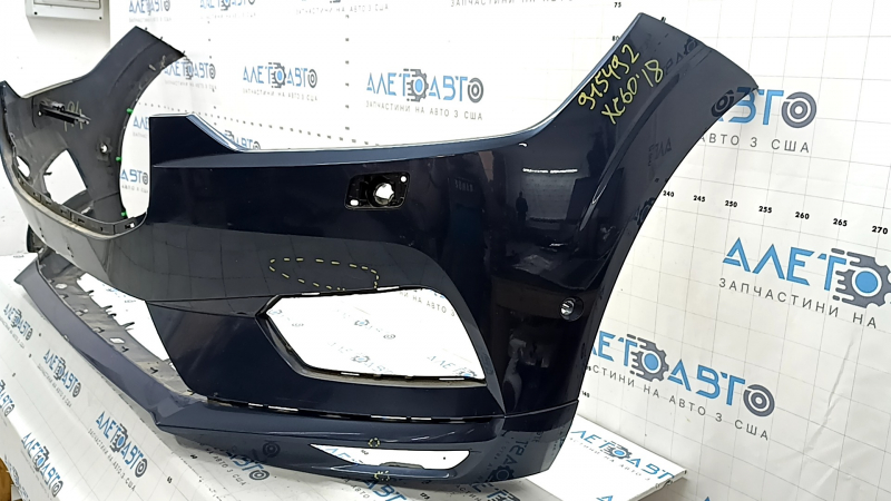 Общий вид переднего бампера Volvo XC60 с заметными следами эксплуатации и вмятинами.
